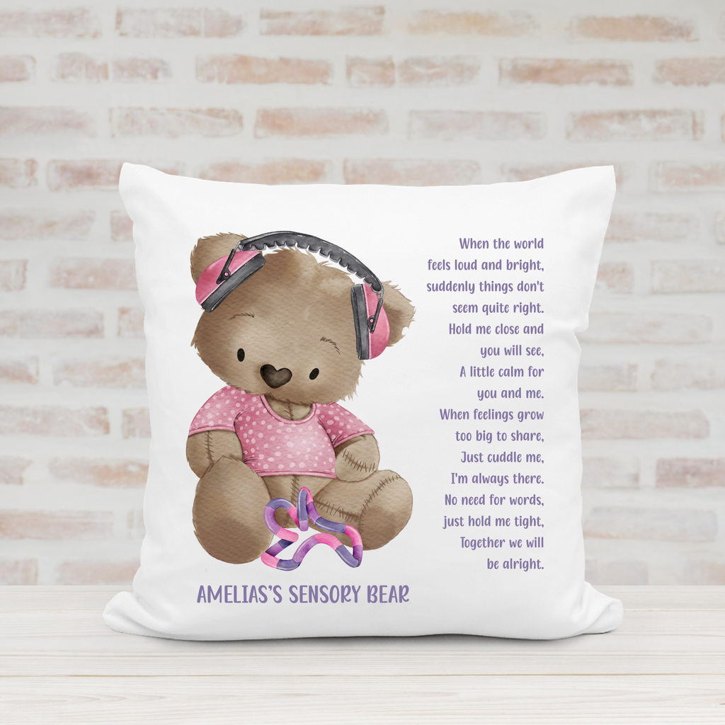 Personalised sensory bear cushion featuring a teddy in a pink T-shirt with pink ear defenders, comforting poem and child's name.