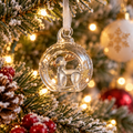 Clear glass reindeer Christmas bauble with gold detail hanging on festive Christmas tree
