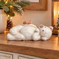 Daisy cream resin bear ornament lying on her back with two pink birds, displayed on a wooden sideboard in a cosy home.
