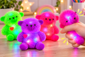 Colourful light up squishy spiky teddy bear fidget toys in green, purple and pink with flashing LED lights.