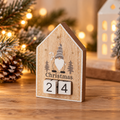 House-shaped wooden Christmas countdown block featuring a grey and white gonk, grey Christmas trees and two numbered wooden cubes, displayed in a cosy festive setting.