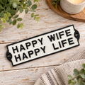Happy Wife Happy Life cast iron wall sign with raised black lettering on a cream vintage-style plaque, displayed on a rustic whitewashed wooden background.