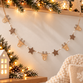 Wooden Christmas garland featuring natural wood reindeer with silver glitter antlers, brown polka dot stars and white beads on twine, displayed in a cosy festive home.